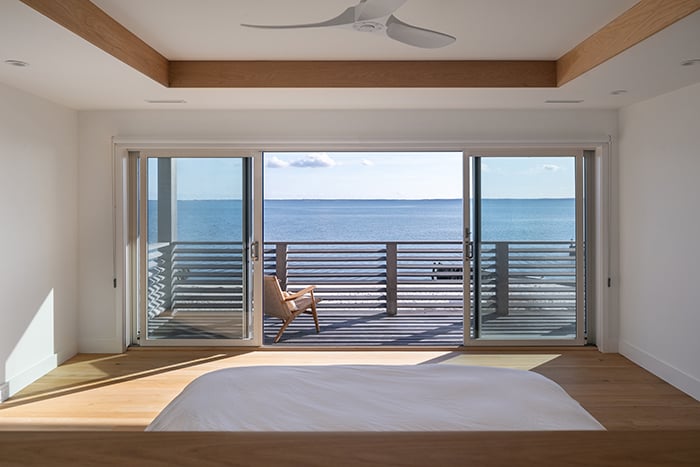 An open gliding patio door leading to a balcony with views of the water.