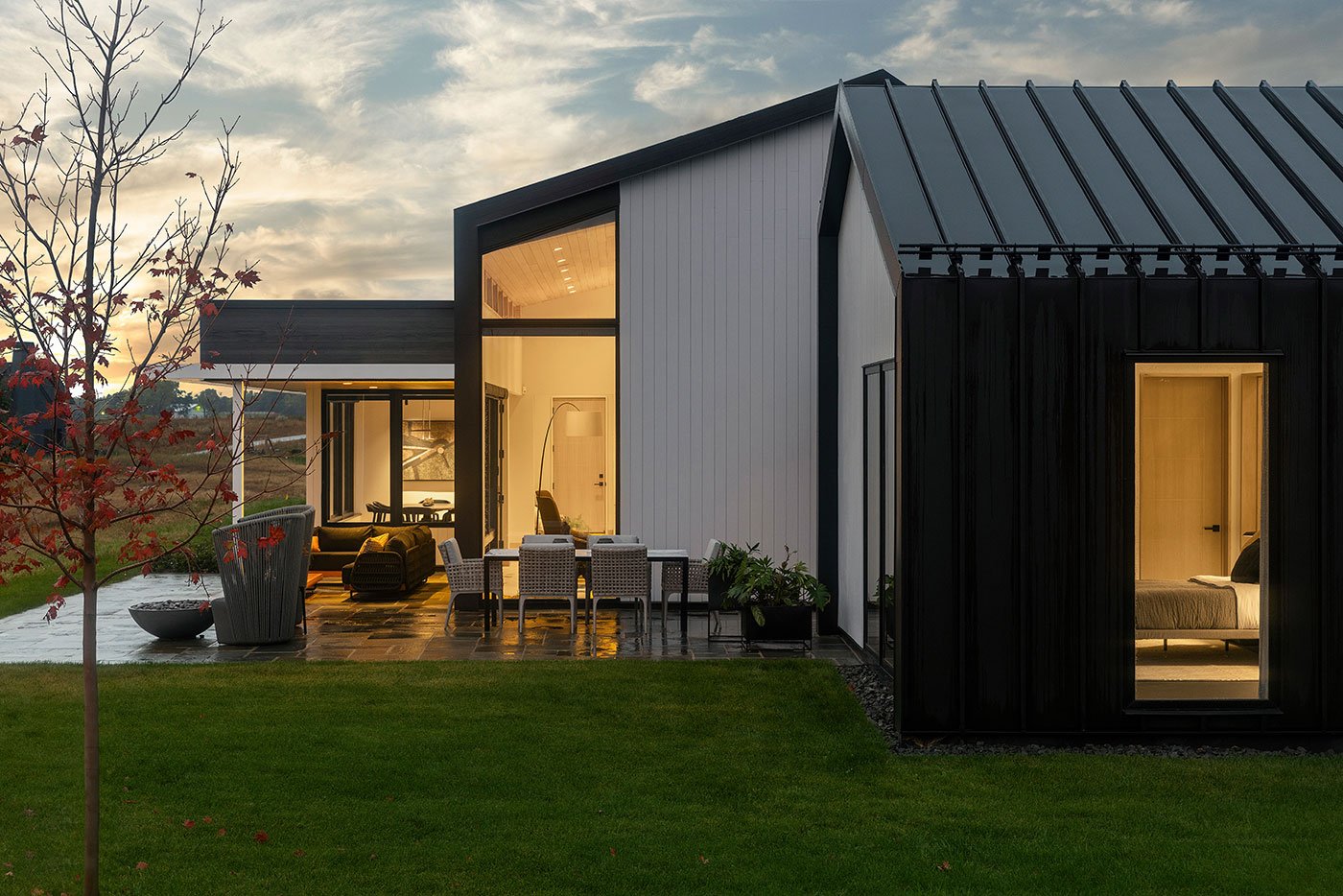 An exterior shot of the home showing the home’s unique profile and patio, which features distinct rooms for eating, hanging out, and enjoying a fire.