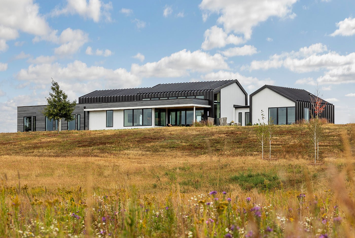An exterior view of the home as seen from the rear with prairie in the foreground.
