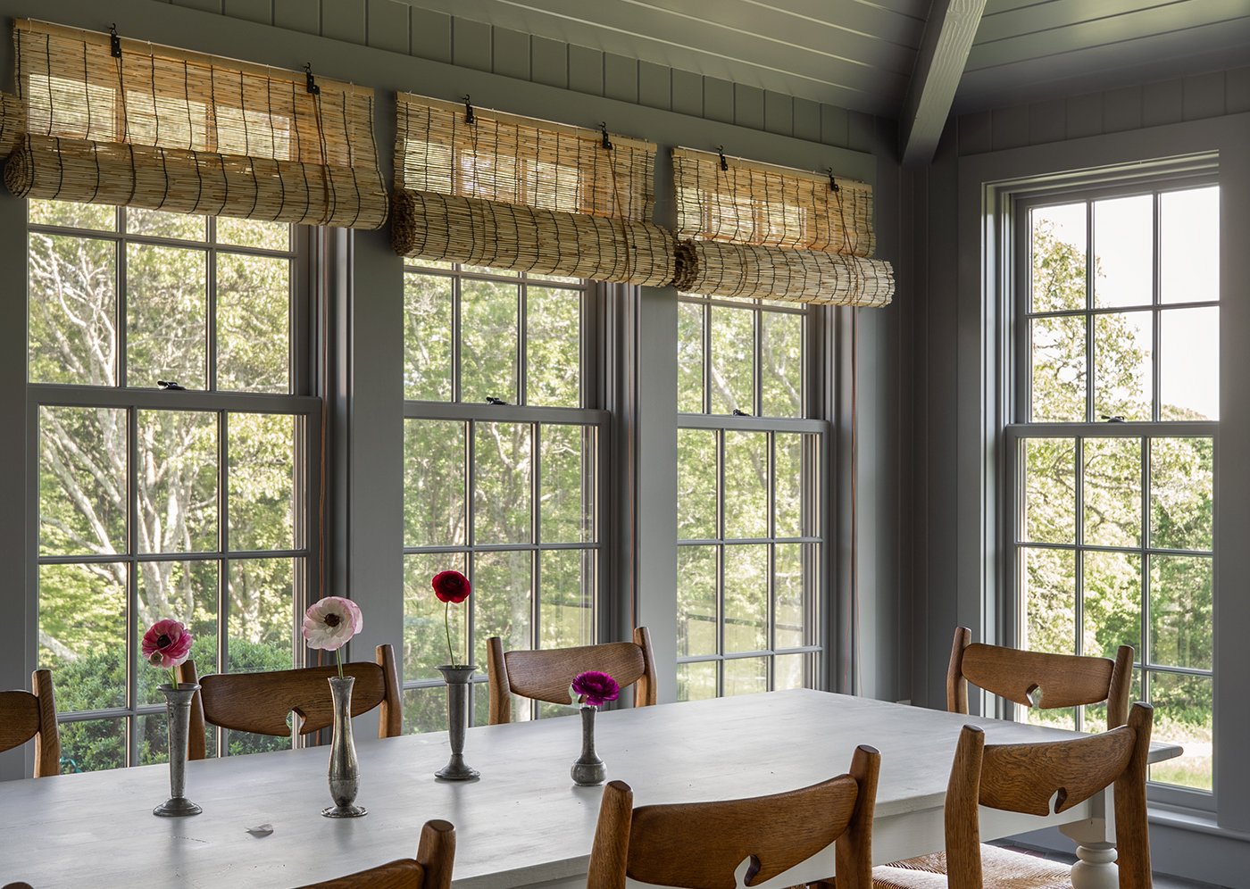 A sunroom with dining table and large Andersen A-Series Double-Hung Windows with cottage sashes.