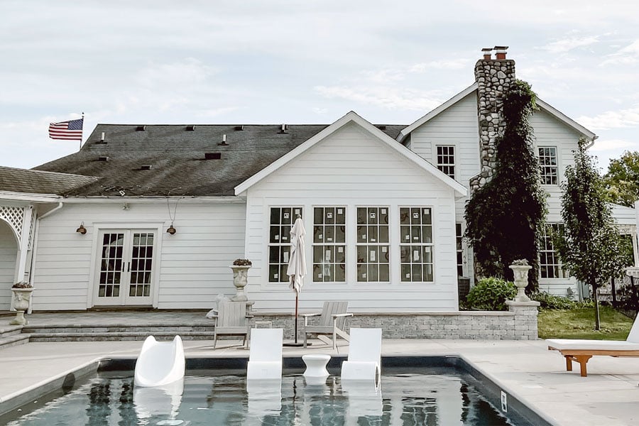 Liz Marie Galvan’s farmhouse viewed from the back where a new addition featuring a primary suite with Andersen windows sunroom faces the swimming pool
