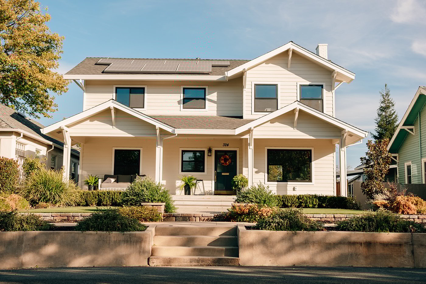 A white farmhouse with black Andersen 100 Series windows.
