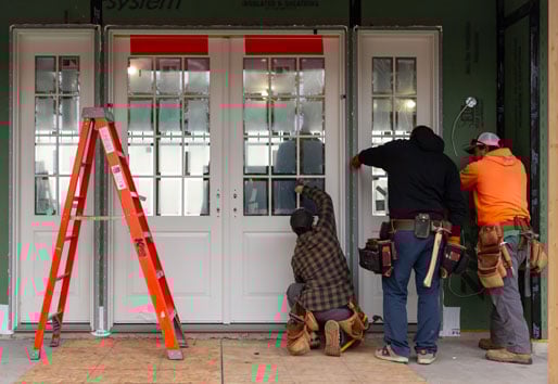 Three men installing a two-panel front door with sidelights on a home with Zip System WRB.