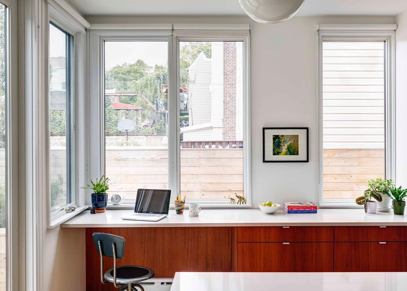 A kitchen/office with cherry cabinetry, white quartz countertops, and large casement windows that flood the space with natural light.