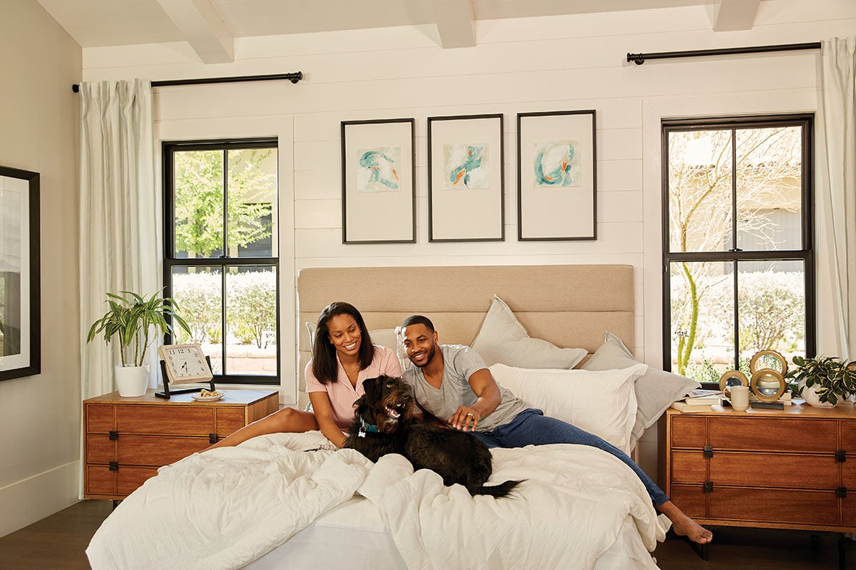 People and dog inside a white home with black 100 series double-hung windows with black grilles
