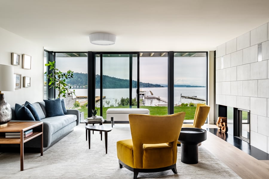 A living room with a wall of glass created by an Andersen® E-Series Gliding Patio Door flanked by stationary panels that wrap around a corner.