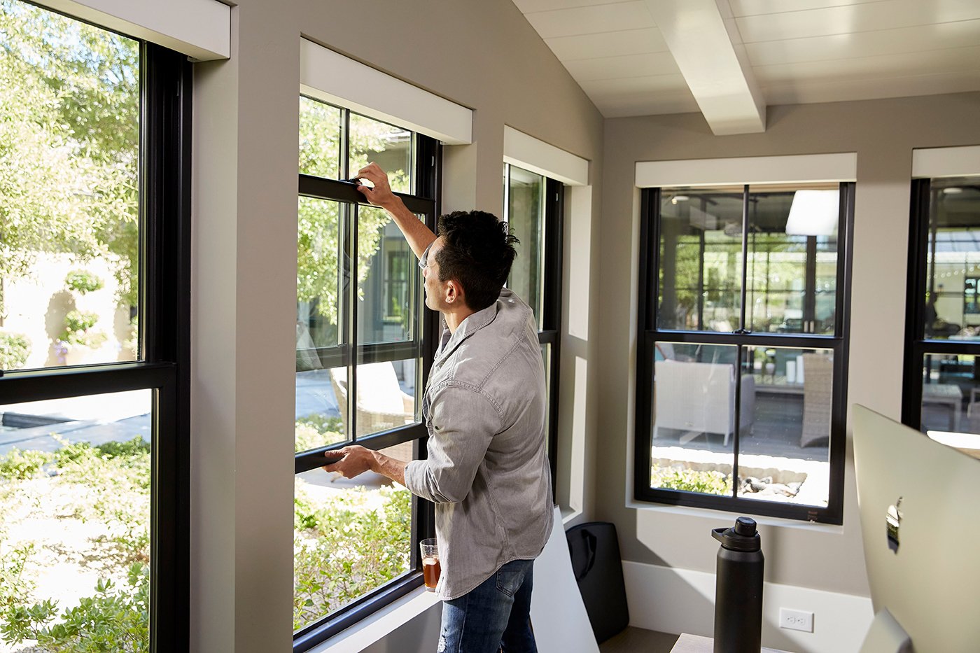 Man opening single-hung window on a beautiful day
