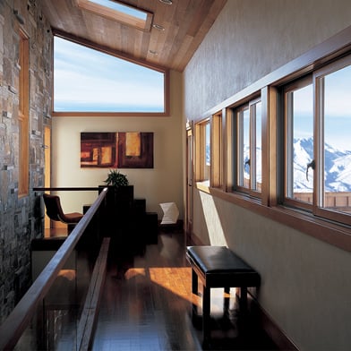 A hallway lined with Andersen® 400 Series Gliding Windows that overlook a dramatic mountain landscape.