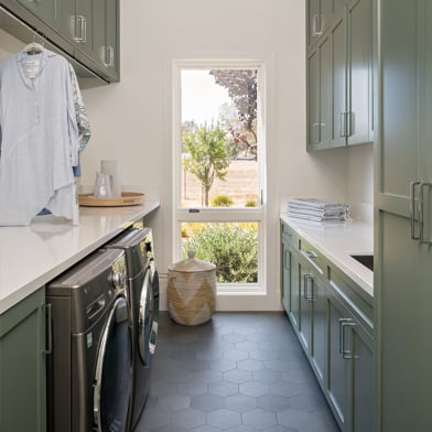 Narrow laundry room with tall casement window at the end letting in natural light
